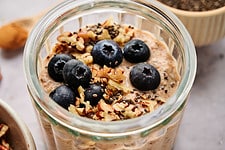 Breakfast Chia Pudding in a glass jar topped with fresh blueberries and pecans.