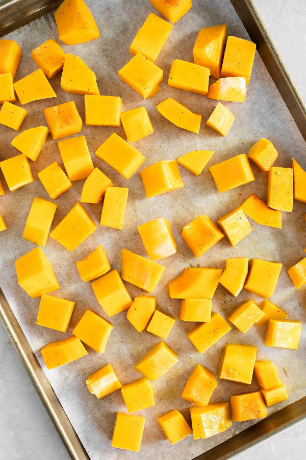 Butternut squash cubes arranged on a baking sheet.