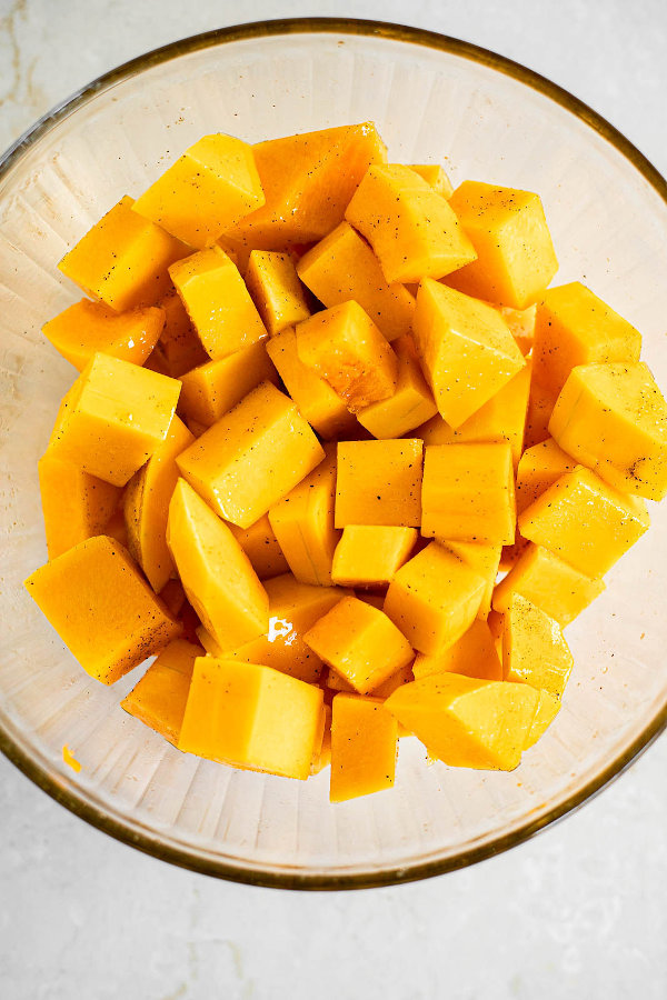 Seasoned butternut squash in a glass bowl.