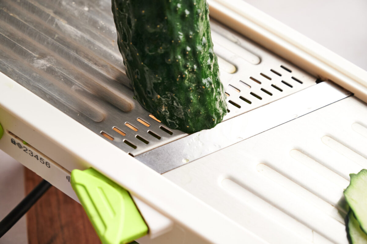 Slicing a cucumber on a mandolin slicer.