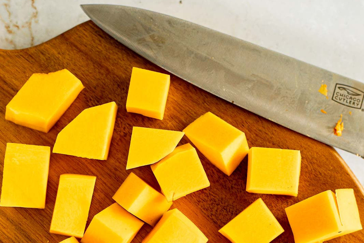 Butternut squash cut into cubes on a cutting board.