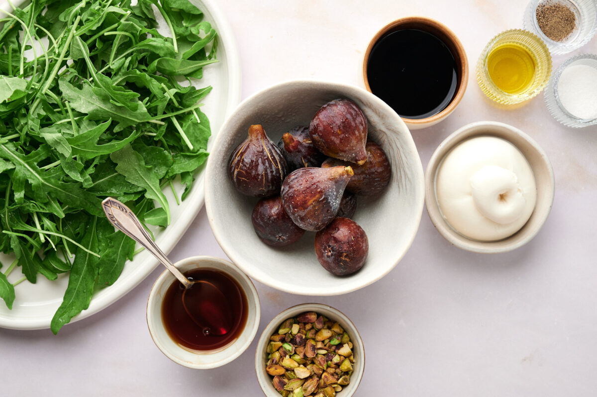 Ingredients for a fig and arugula salad with burrata and pistachios.