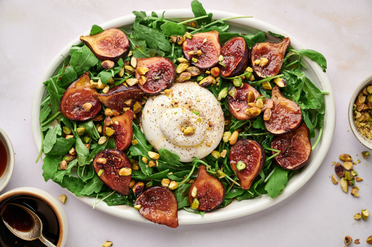 Fig & Arugula Salad with Burrata on a white platter.