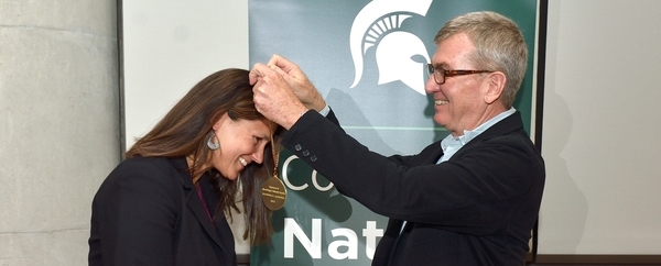 Vice President Gage placing medal around a female faculty member