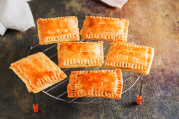 Homemade pop tarts made from scratch cooling off on a wire rack on a table.