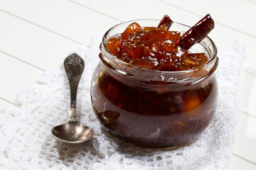 Kumquat marmalade in a glass jar with a spoon.