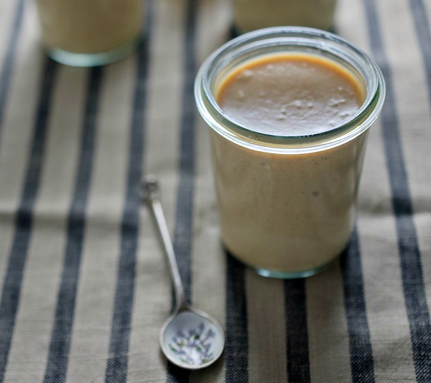 A jar filled with pumpkin panna cotta with a spoon. 