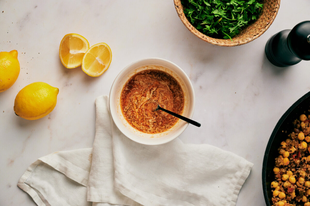 Sauce in a bowl with a spoon for quinoa stuffed eggplants.