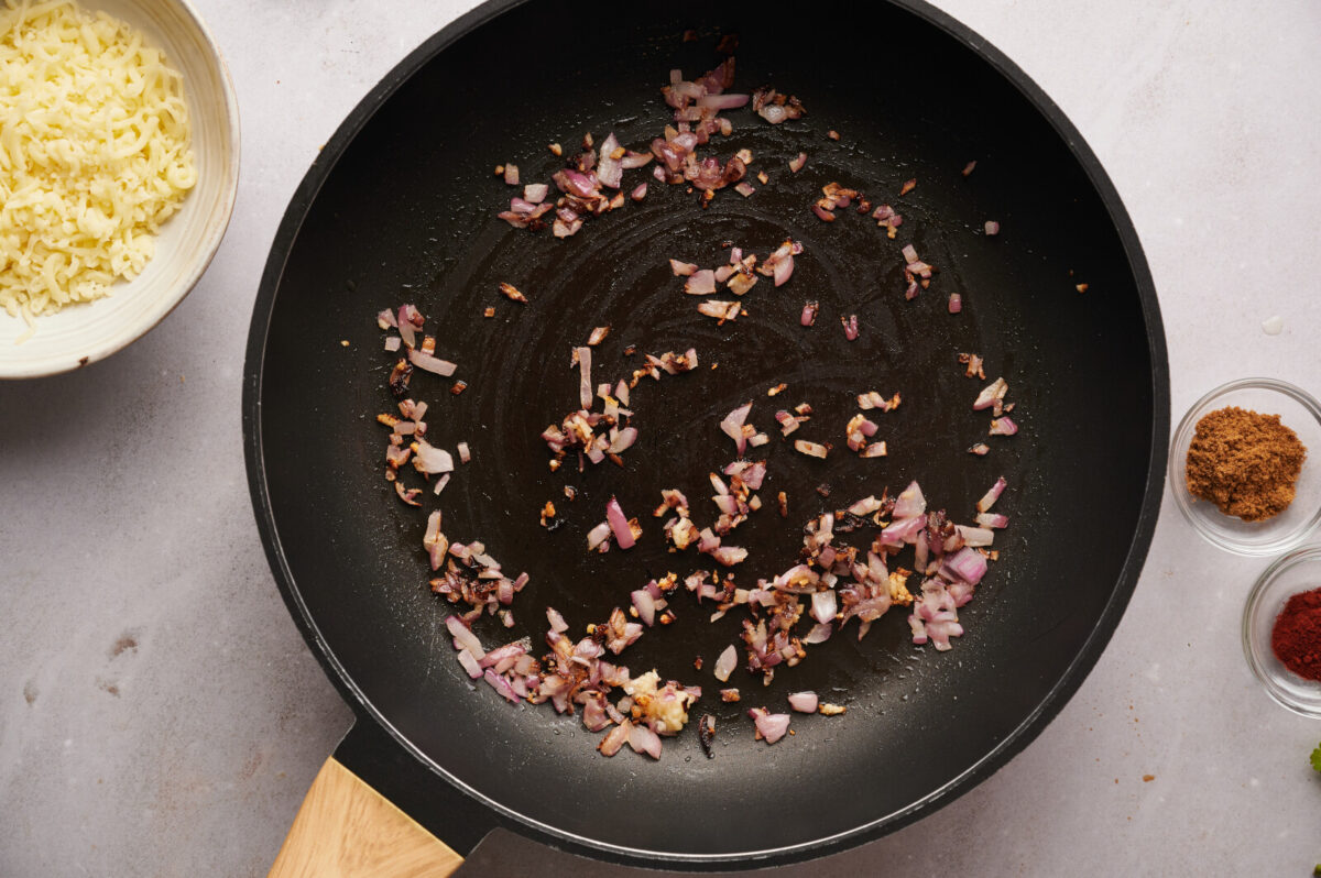 Red onion and garlic being sautéed in a skillet.