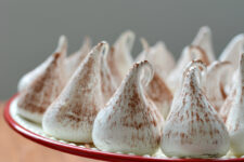 ac ropped image of a batch of swiss meringue kisses arranged on top of the cake table