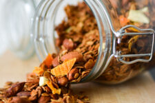 cropped image of a glass canister lying on its side, filled with a mixture of overflowing rolled oats and whole almonds