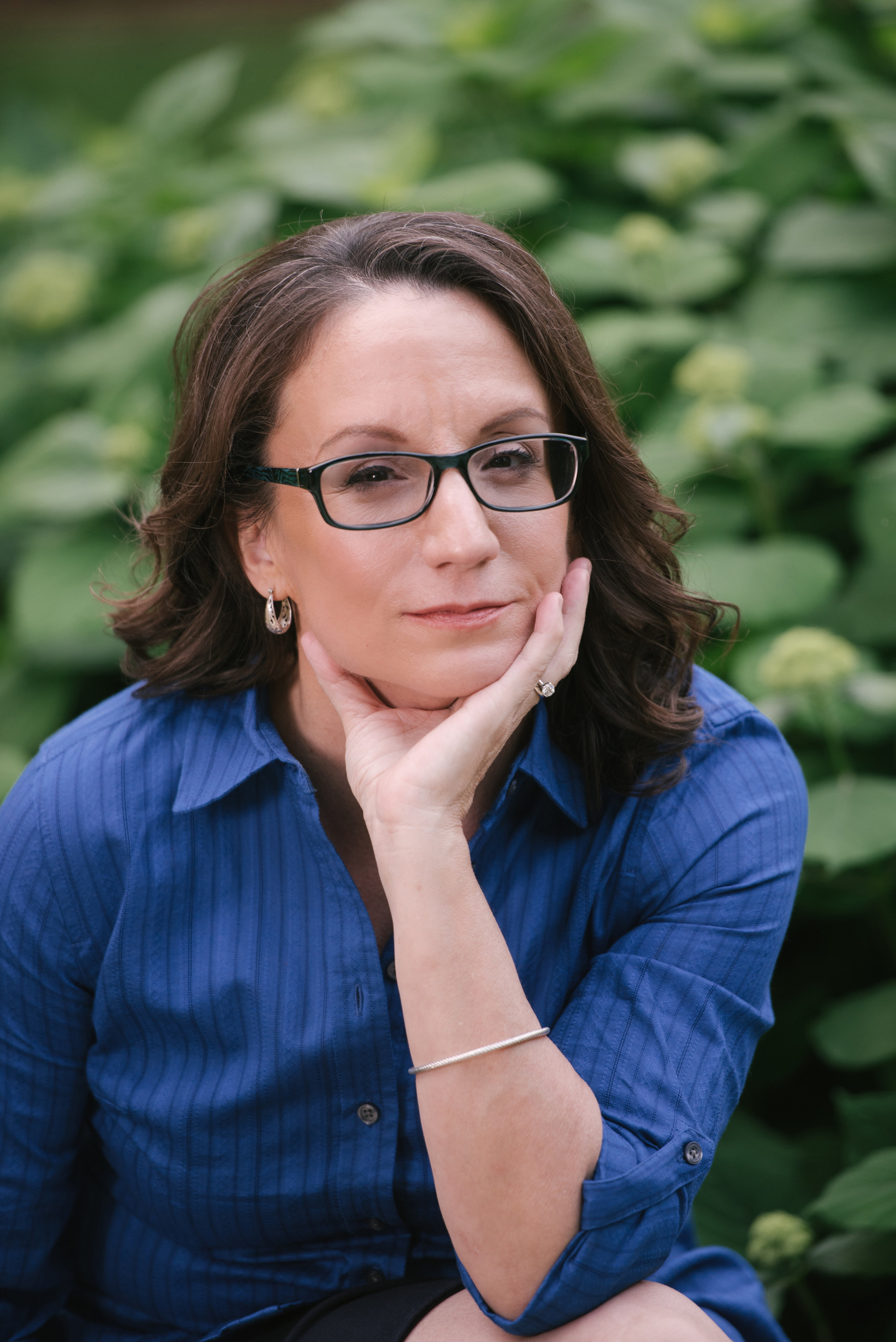 Woman with dark hair and glasses in blue top