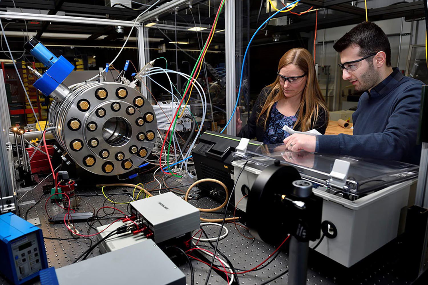 Two people looking at various technological machines. 