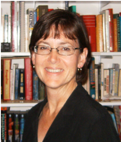 A woman with short brown hair and glasses, wearing a dark top, standing in front of a bookcase