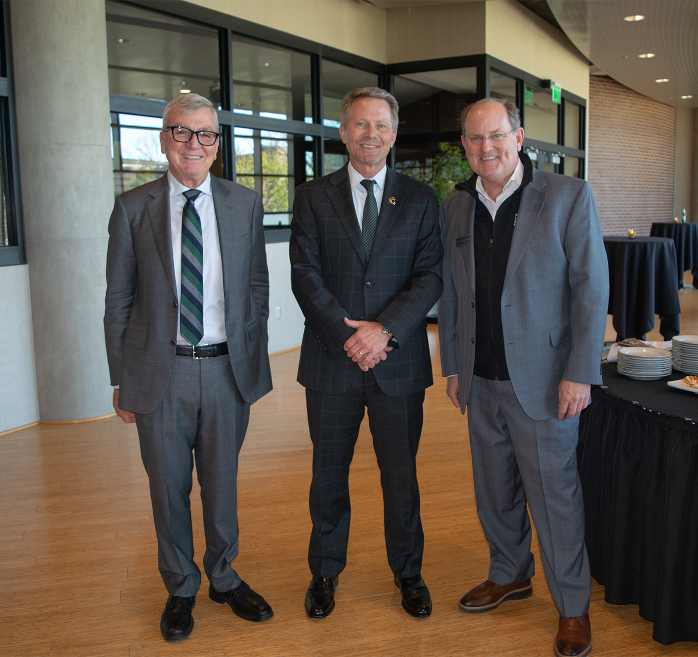 Three men wearing suits, standing together. 