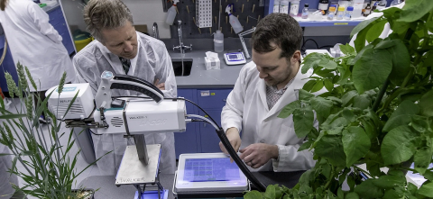 Berkley Walker and the MSU President looking at a piece of equipment in a lab