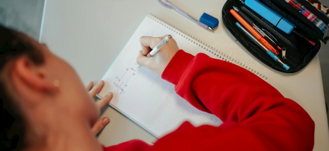 Student writes with pen on graph paper